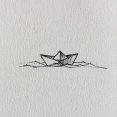 an origami boat floating in the water on top of a white sheet of paper