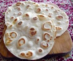 three flat breads sitting on top of a wooden cutting board with holes in them