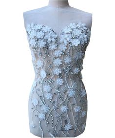 a white dress with flowers and beads on the bust, it is made out of mesh