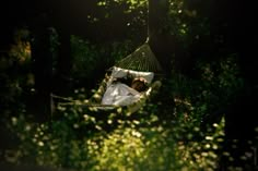 a woman laying in a hammock on top of a lush green forest filled with trees