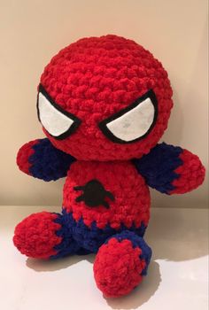 a crocheted spider - man stuffed animal sits on a white surface with eyes wide open