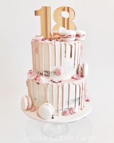 a three tiered cake with white frosting and pink flowers on the bottom layer