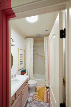 a bathroom with pink and yellow decor on the walls