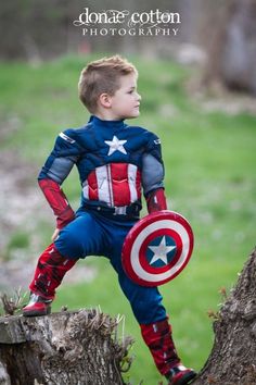 a little boy dressed up as captain america standing on a tree stump in the woods