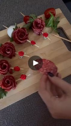 someone is decorating flowers on a cutting board with toothpicks and other items