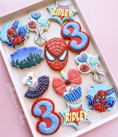 decorated cookies in the shape of spider - man and other characters on a white tray