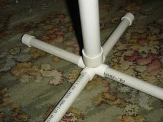 a close up of a white table with four legs on carpeted floor next to rug