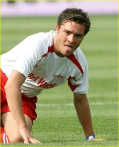 a young man crouching down to catch a frisbee in the grass on a soccer field