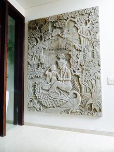 an intricately carved wall panel in the corner of a room with white walls and flooring