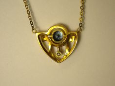 This beautiful Art Deco Style necklace is made of 14K yellow gold. It is handcrafted and features a .88ct bright blue sapphire. Hanging beneath the sapphire is a .08ct diamond. The chain is approximately 9 inches long on each side of the pendant, and attached to each side, rather than through a bail. The pendant is 2cm wide and 1.9cm long. It is 1.5mm thick. Markings: stamped 14K Unique Blue Necklace With Polished Finish, Art Deco Gold Sapphire Jewelry, Gold Blue Topaz Jewelry With Polished Finish, Heirloom Blue Necklaces For Weddings, Collectible Gold Sapphire Jewelry, Gold Tanzanite Necklace For Anniversary, Gold Sapphire Necklace Hallmarked, Unique Yellow Gold Jewelry With Blue Topaz, Art Deco Sapphire Jewelry Gift