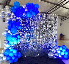 blue and silver balloons are in front of a large wall with sequins on it