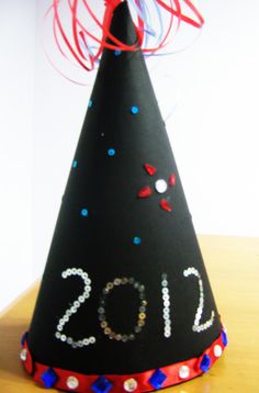 a black party hat with red, white and blue streamers on it that says 2012