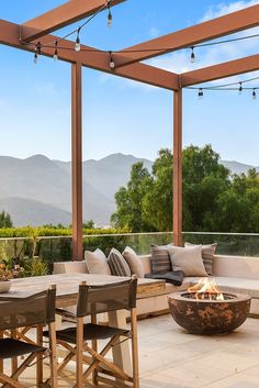 an outdoor seating area with fire pit and mountains in the background