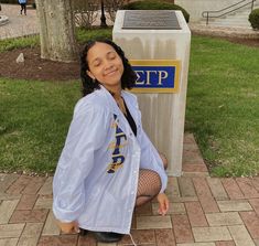 a young woman sitting on the ground next to a mailbox with her eyes closed