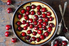 a cake with cherries on it sitting in a pan next to spoons and forks