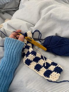 someone is crocheting the blue and white afghan on their bed while knitting it