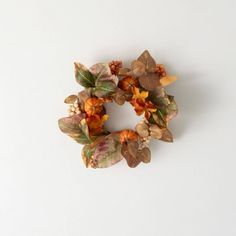 a close up of a wreath made out of leaves and flowers on a white surface