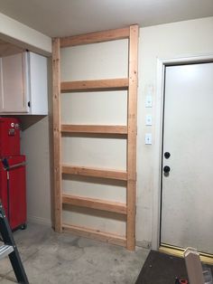 an unfinished kitchen with white cabinets and red refrigerator in the corner, next to a ladder