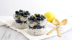 three jars filled with blueberries and oatmeal on top of a white napkin