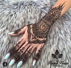 a woman's hand with henna tattoos on it