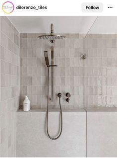 a shower head and hand held shower faucet in a bathroom with tiled walls