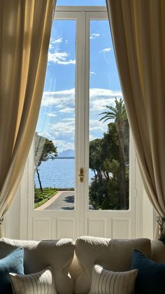 a living room filled with furniture and a large window overlooking the ocean on a sunny day