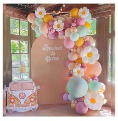 an arch made out of balloons and flowers with a vw bus in the background