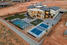 an aerial view of a house with a tennis court and pool in the foreground