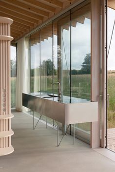 a modern kitchen in front of large windows with glass doors on the outside and inside