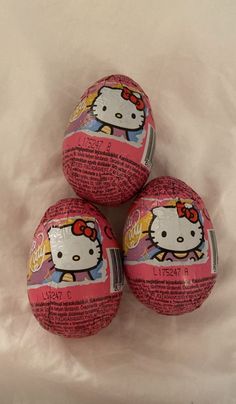 three hello kitty easter eggs on a white sheet