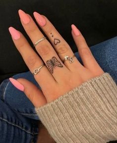 a woman's hand with four different tattoos on her fingers and two rings in the middle