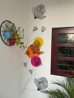 a wall with flowers painted on it next to a potted plant