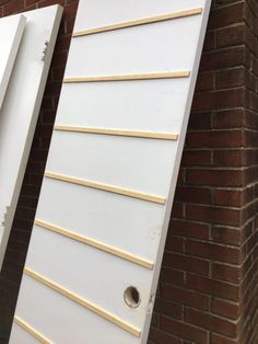 two white doors with wooden slats in front of a brick wall and one closed