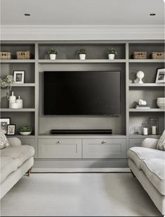 a living room with two couches and a flat screen tv on the wall in front of it