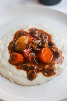 a white plate topped with mashed potatoes and meat