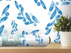 blue watercolor leaves on white wallpaper next to potted plant and rolled up wrapping paper