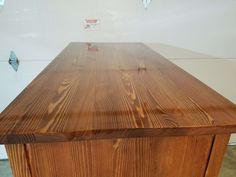 a large wooden table sitting in the middle of a room next to a white wall