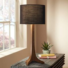 a wooden table with a lamp on top of it next to a potted plant