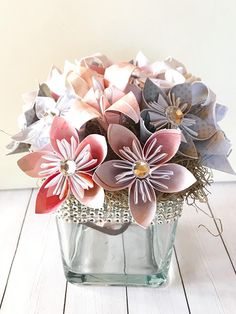 a vase filled with paper flowers on top of a wooden table