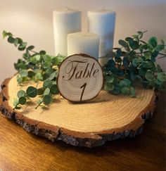 a wooden table with candles and greenery on it, next to a sign that says table 1