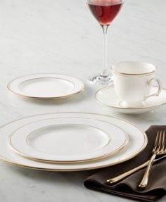 there is a glass of wine on the table with plates and silverware next to it