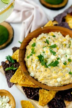 a wooden bowl filled with dip surrounded by tortilla chips