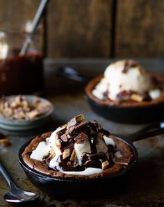 three skillets filled with ice cream, chocolate and nuts on top of a table