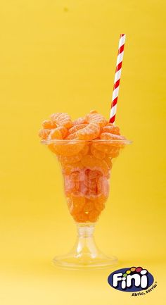 a glass filled with orange candy on top of a yellow background