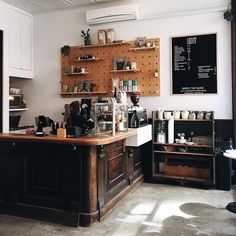 a coffee shop with lots of counter space and wooden shelves on the wall above it