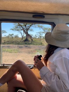 a woman sitting in the back seat of a vehicle looking at a giraffe