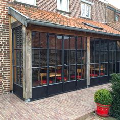 an outdoor dining area with tables and chairs in front of a brick building that has large windows