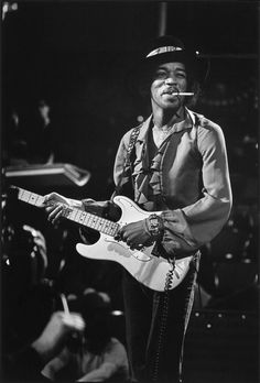 a black and white photo of a man playing an electric guitar with his mouth open