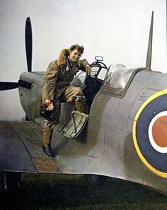 a man sitting on the wing of an old fashioned fighter plane with luggage in his hand