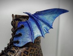 a shoe with a blue dragon wing on it's boot laces and leopard print boots